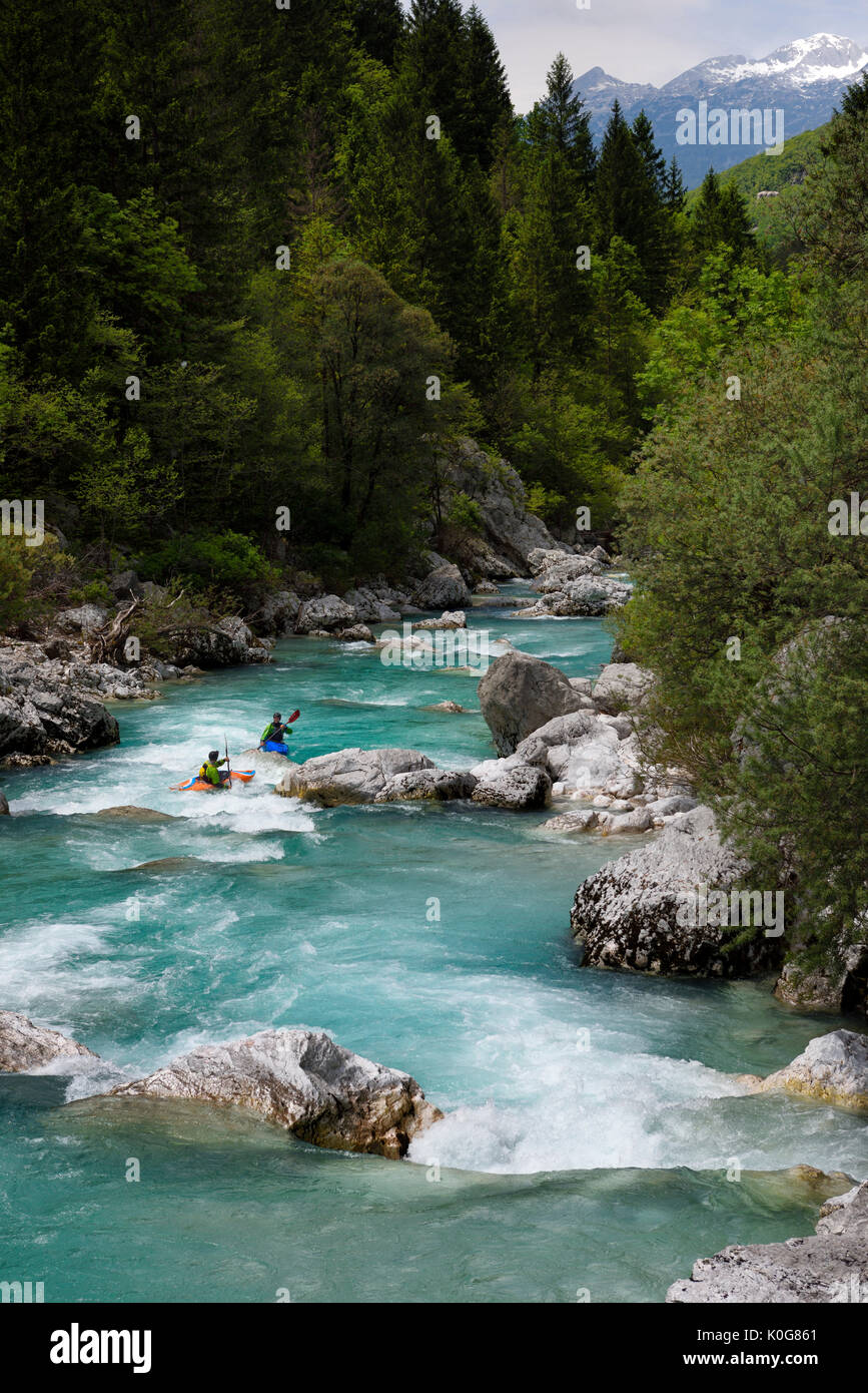 Kayakers paddling il freddo verde smeraldo acqua alpina della tomaia Soca River vicino a Bovec Slovenia con Kanin montagne delle Alpi Giulie Foto Stock