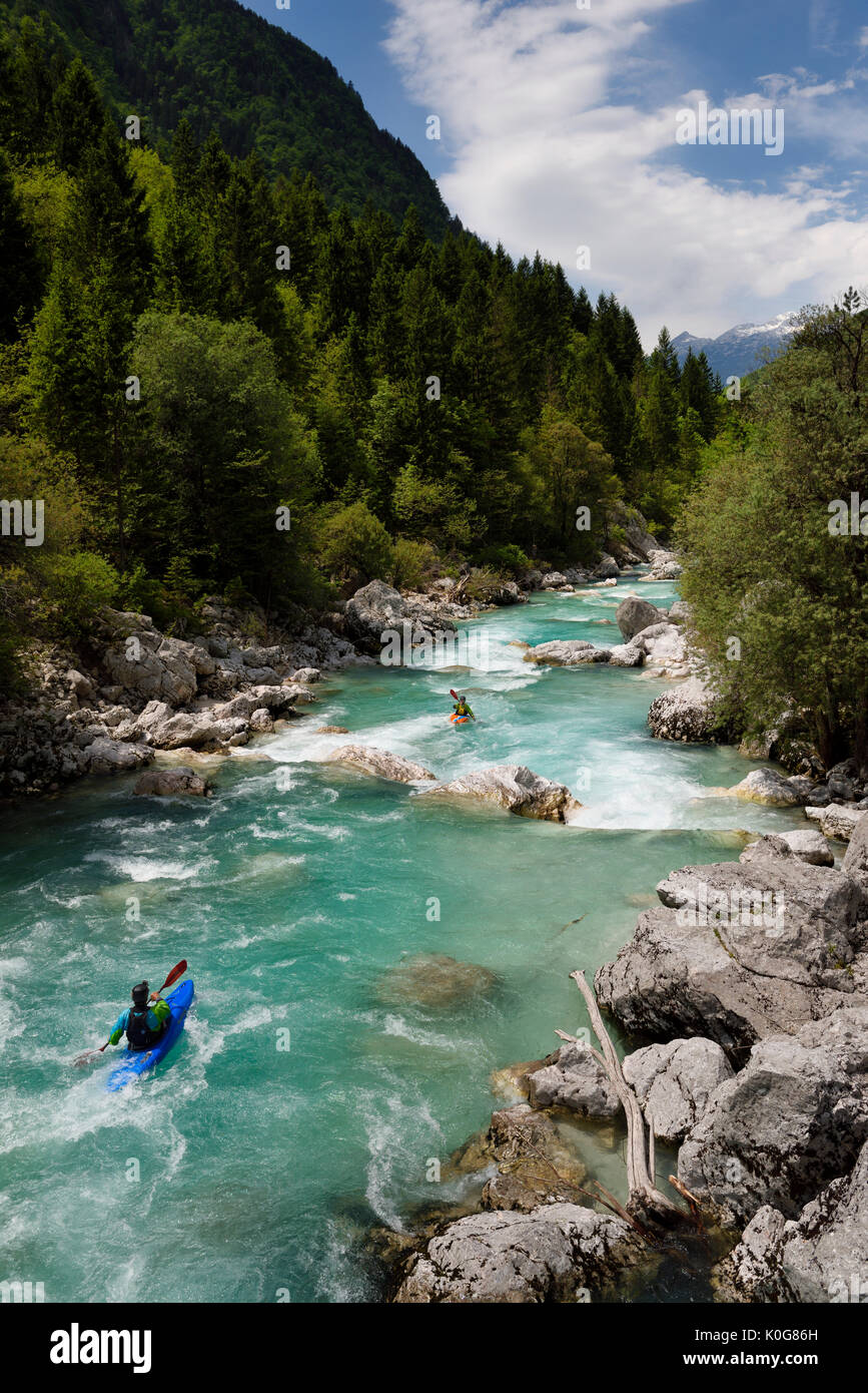 Kayakers riprese il freddo verde smeraldo acqua alpina della tomaia Soca River vicino a Bovec Slovenia con Kanin montagne delle Alpi Giulie Foto Stock