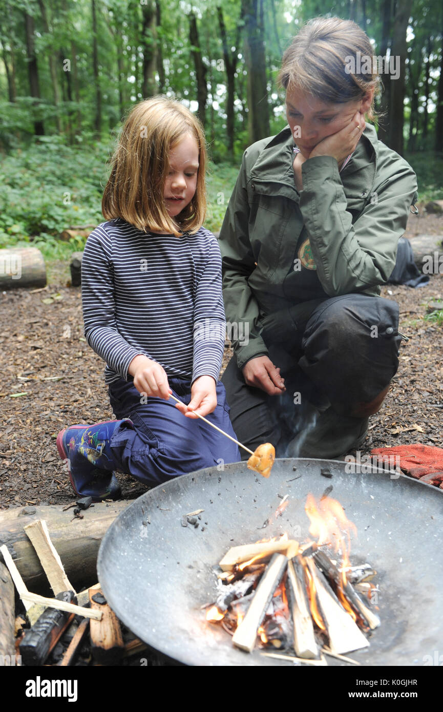 Ragazza e la sua mamma tostare pane al cioccolato sopra una fossa di incendio di boschi in una scuola della foresta vicino a Charlbury. U.K. Foto Stock
