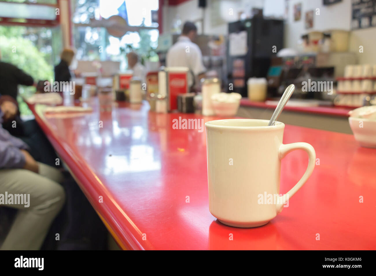 Un bianco tazza di caffè con un cucchiaio all'interno su un tavolo bar all'interno di un tradizionale caffetteria americana, ketchikan. Foto Stock