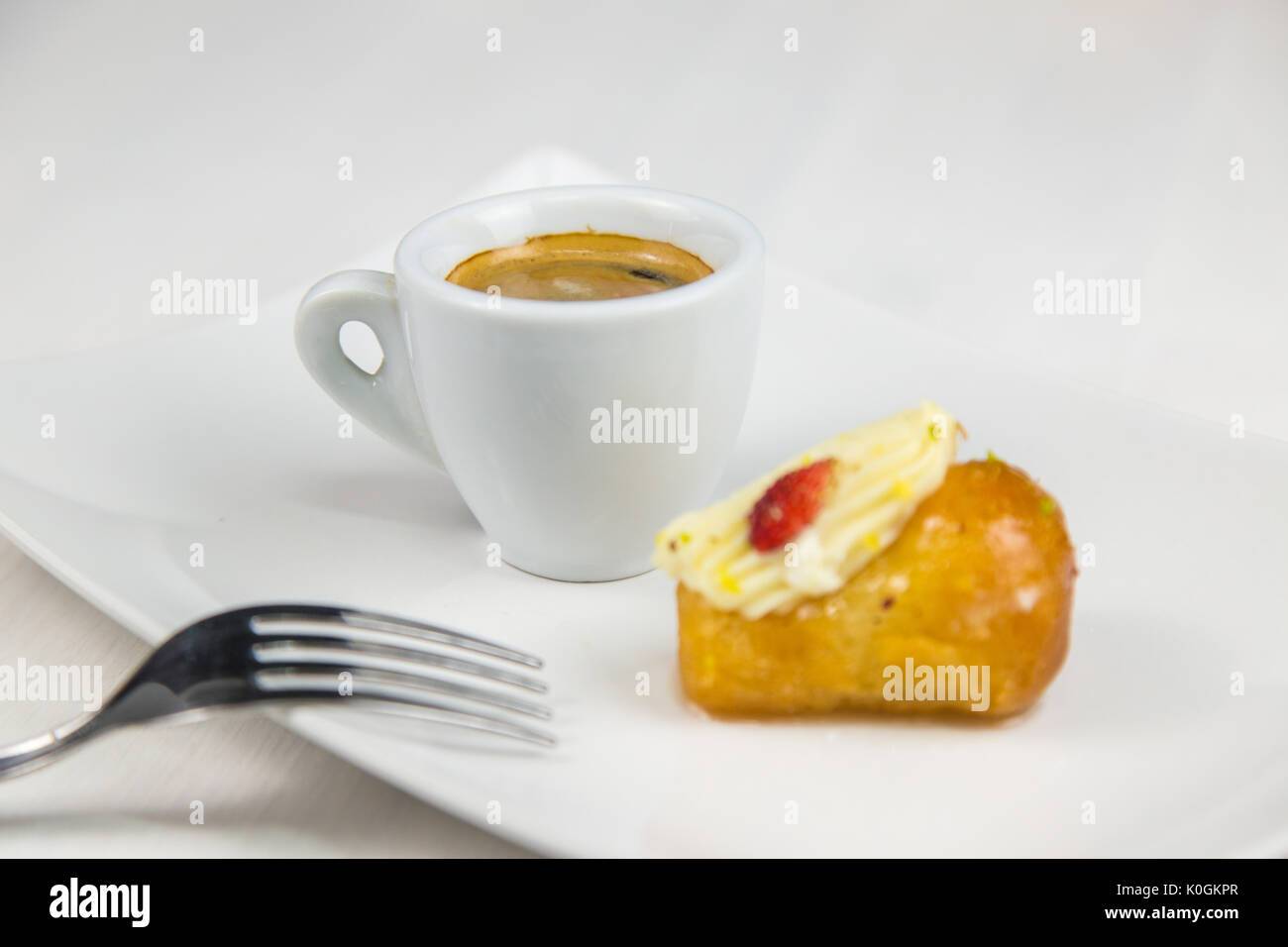 Babà napoletano e caffè sul bianco piatto bianco Foto Stock