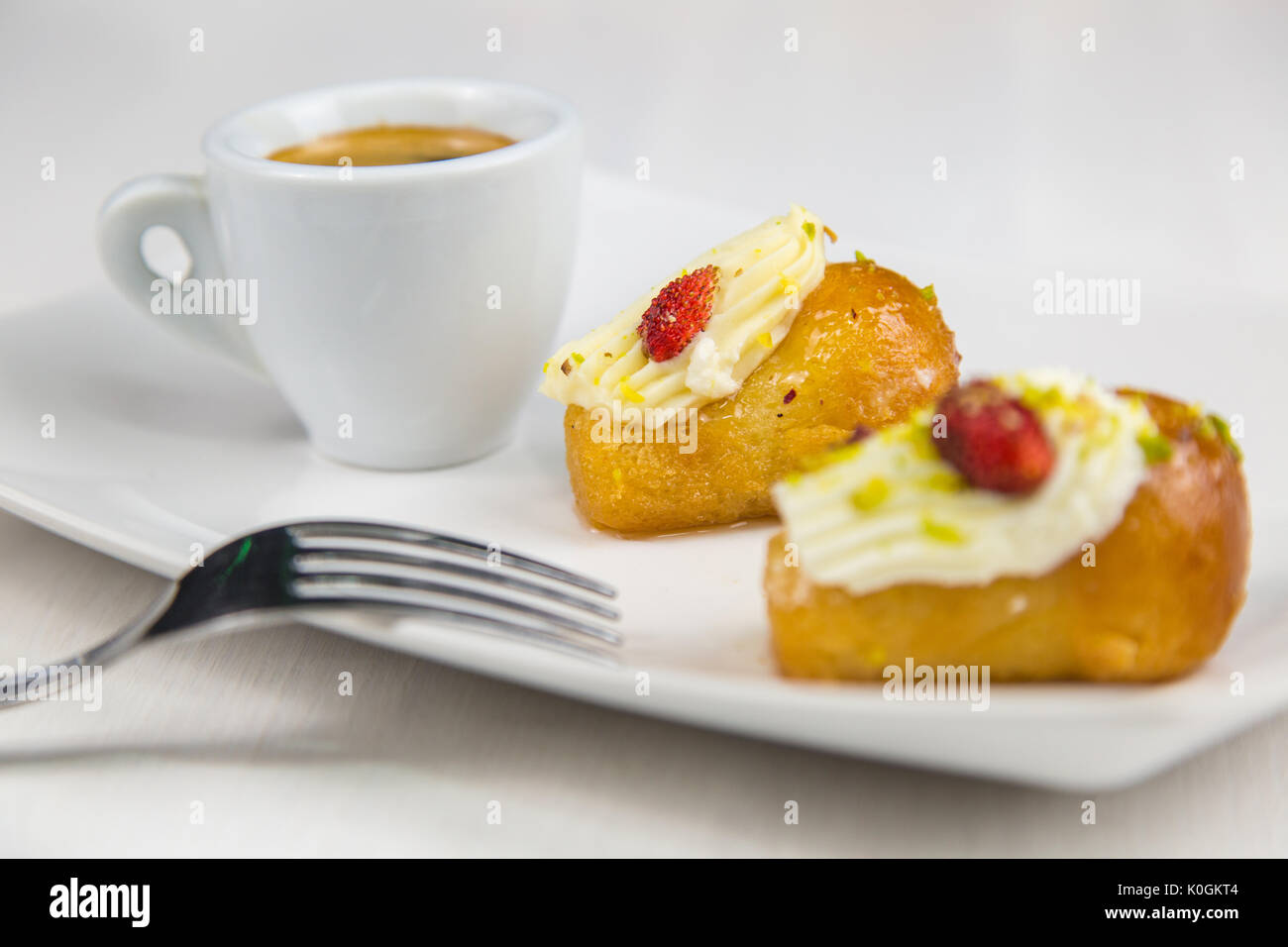 Babà napoletano e caffè sul bianco piatto bianco Foto Stock