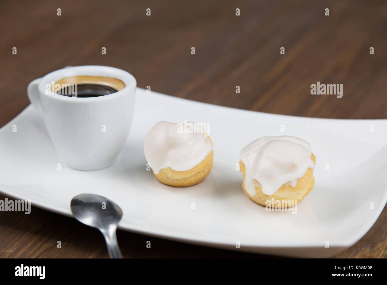 Bignè e caffè sul white white piatto sul tavolo in legno Foto Stock