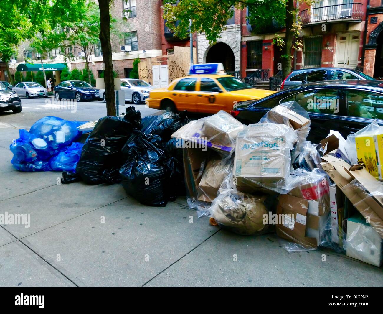 Insaccò, Manhattan garbage posto a lato del marciapiede per regolare del raccoglitore di rifiuti come giallo cabina passa da. Upper Eastside. New York, NY, STATI UNITI D'AMERICA. Foto Stock
