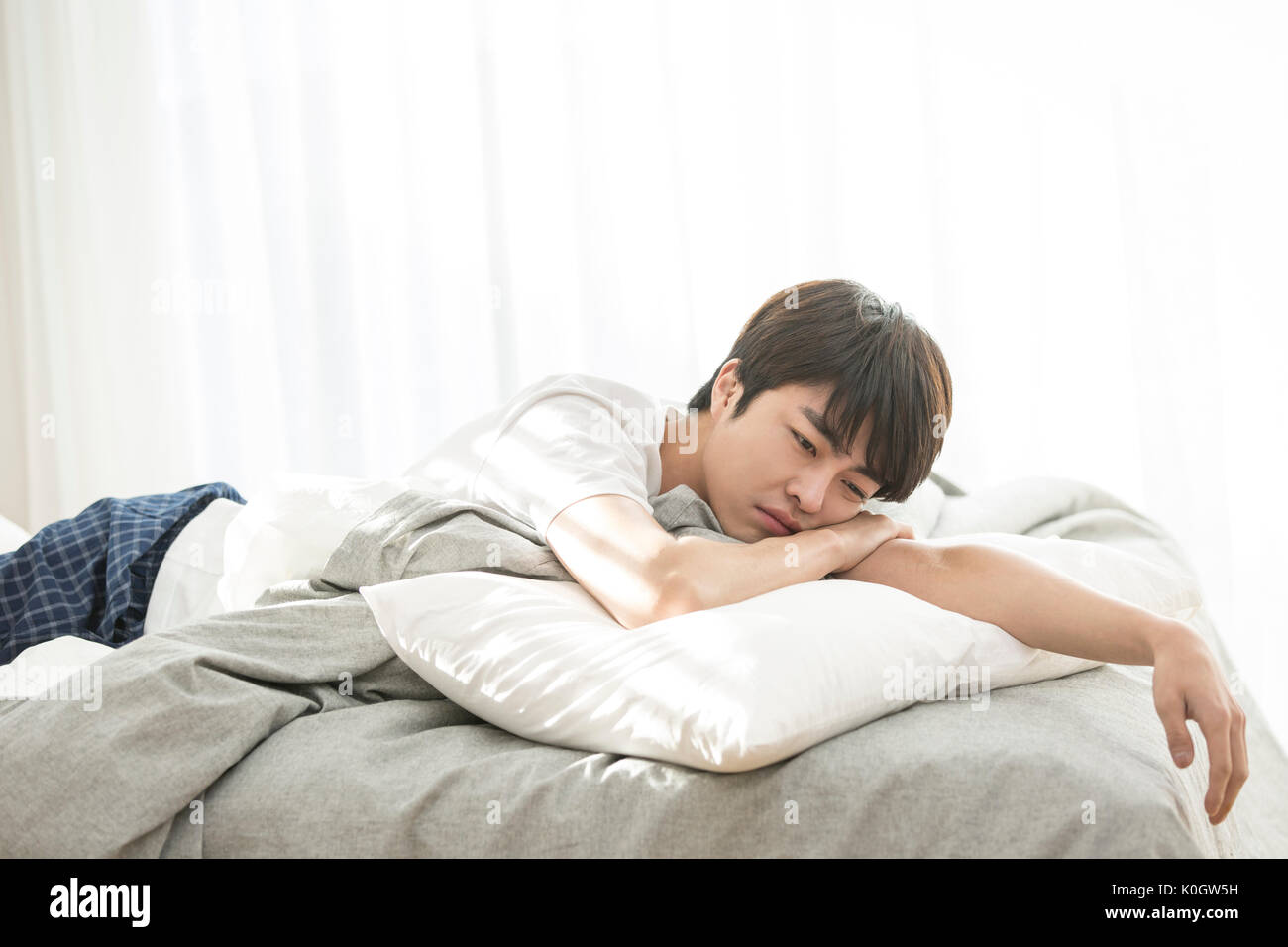 Singolo uomo stanco sdraiato a faccia in giù sul letto Foto Stock