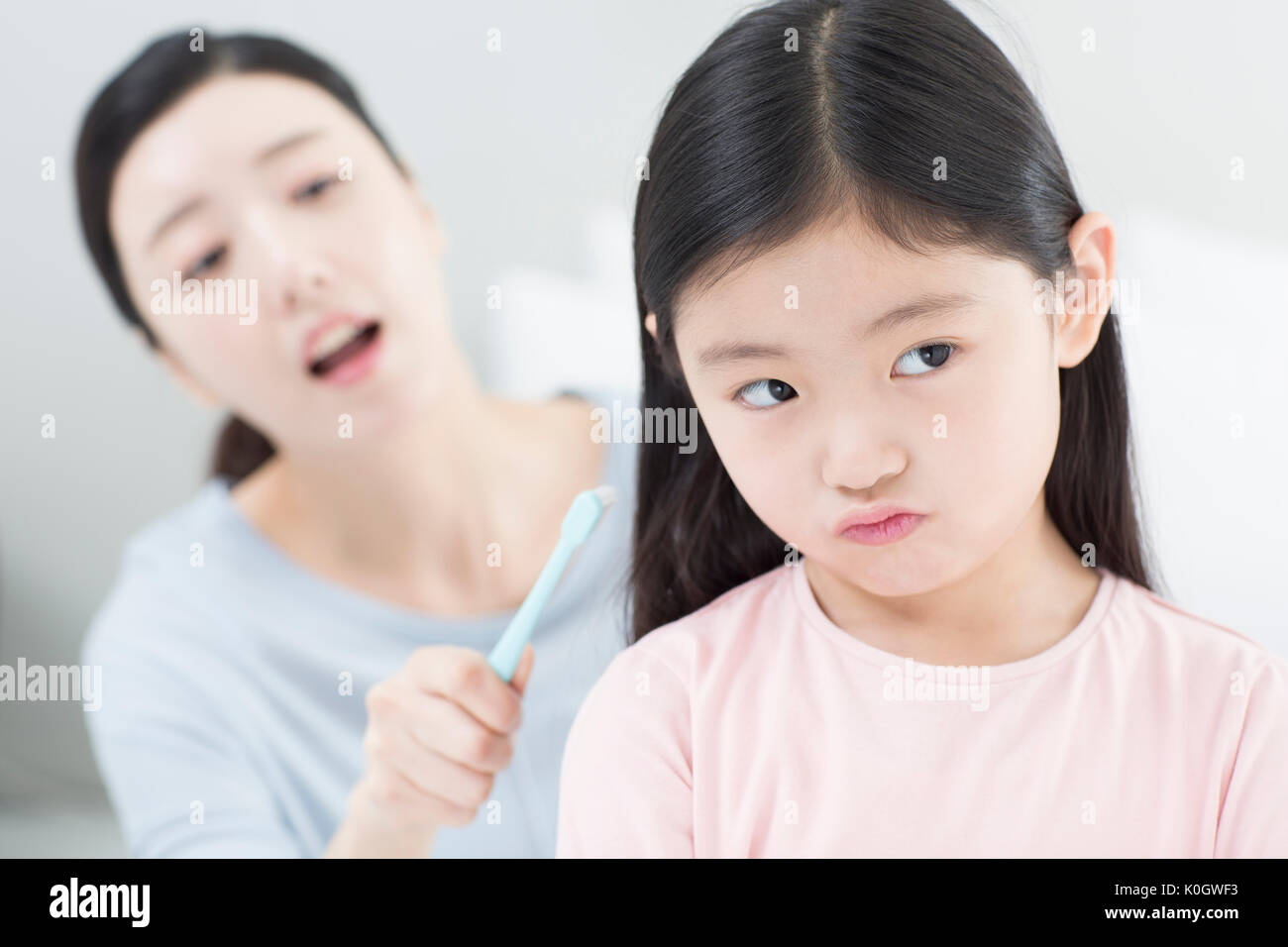 Ritratto di ragazza odiando a spazzolare i denti e sua madre preoccupato Foto Stock