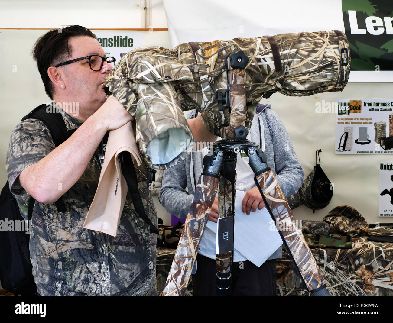 Uomo con pesantemente camuffato di telecamera e obiettivo su un cavalletto per fotografia della fauna selvatica. Foto Stock