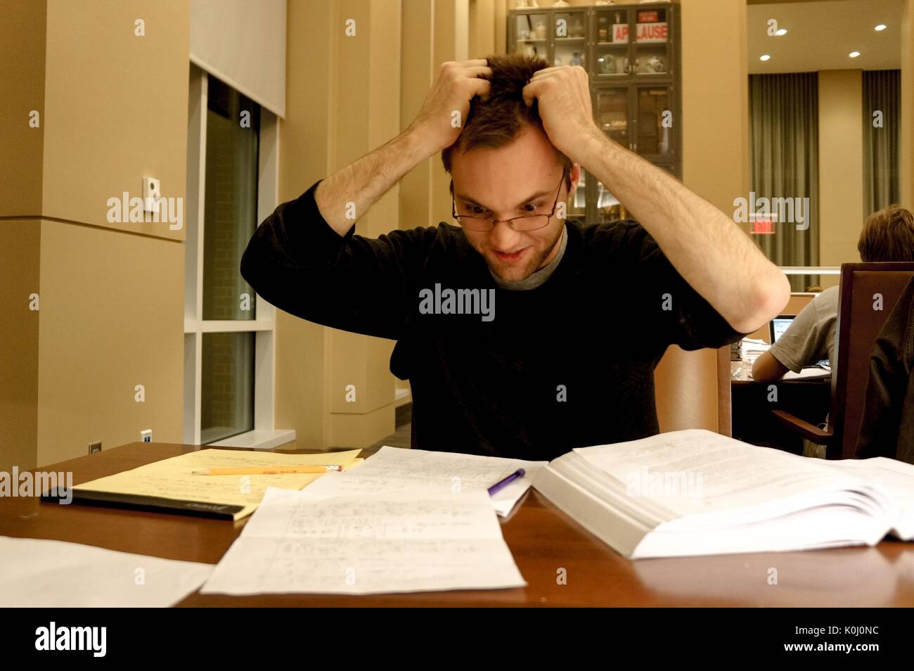 Una sconcertata studente di college afferra i capelli come egli guarda le sue note nella sala di lettura della brody learning commons, un studio di spazio e la libreria su homewood campus della Johns Hopkins University di Baltimore, Maryland, 2015. cortesia eric chen. Foto Stock
