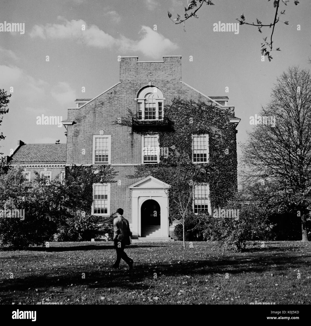 Uno studente passeggiate passato Latrobe Hall, un edificio accademico su Homewood campus della Johns Hopkins University di Baltimora, Maryland. 1940. Foto Stock