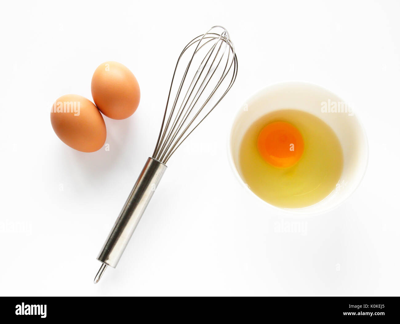 Le uova in una terrina con una frusta Foto Stock