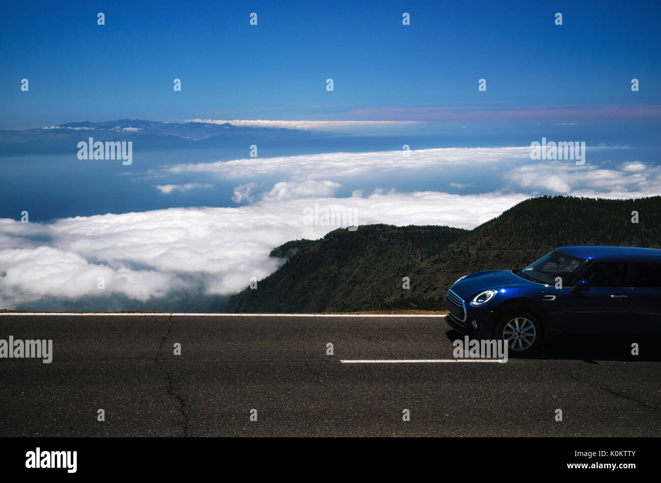 Dark viaggio in auto sulla serpentina di montagna sopra le nuvole lungo il precipizio di Tenerife contro il cielo. Roadtrip intorno alle isole Canarie Foto Stock