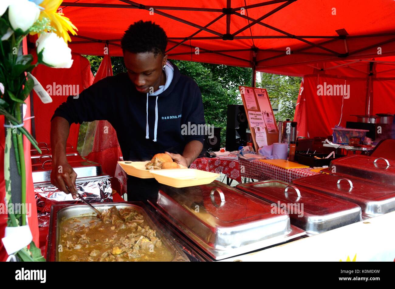 Uomo che serve cibo caraibico ad una street food festival Swansea Food Festival Galles Cymru REGNO UNITO GB Foto Stock