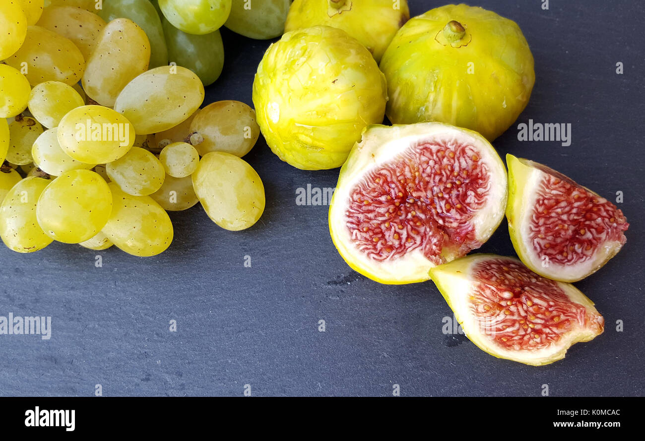 Gruppo di fichi freschi e uva verde scuro sulla tabella Foto Stock