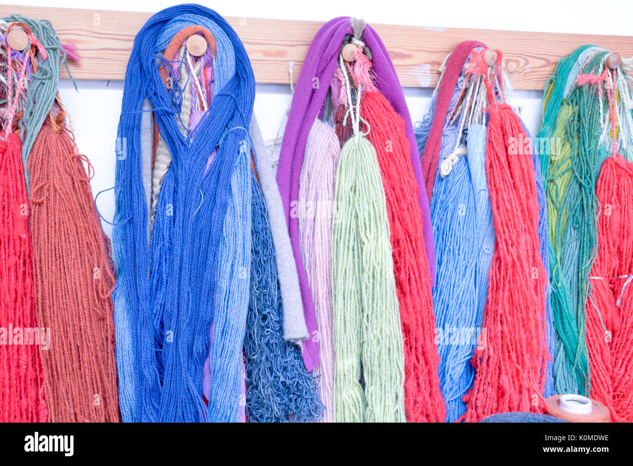 Tinti a mano e handspun lana con una gamma di colori vivaci appeso su pioli in studio Foto Stock