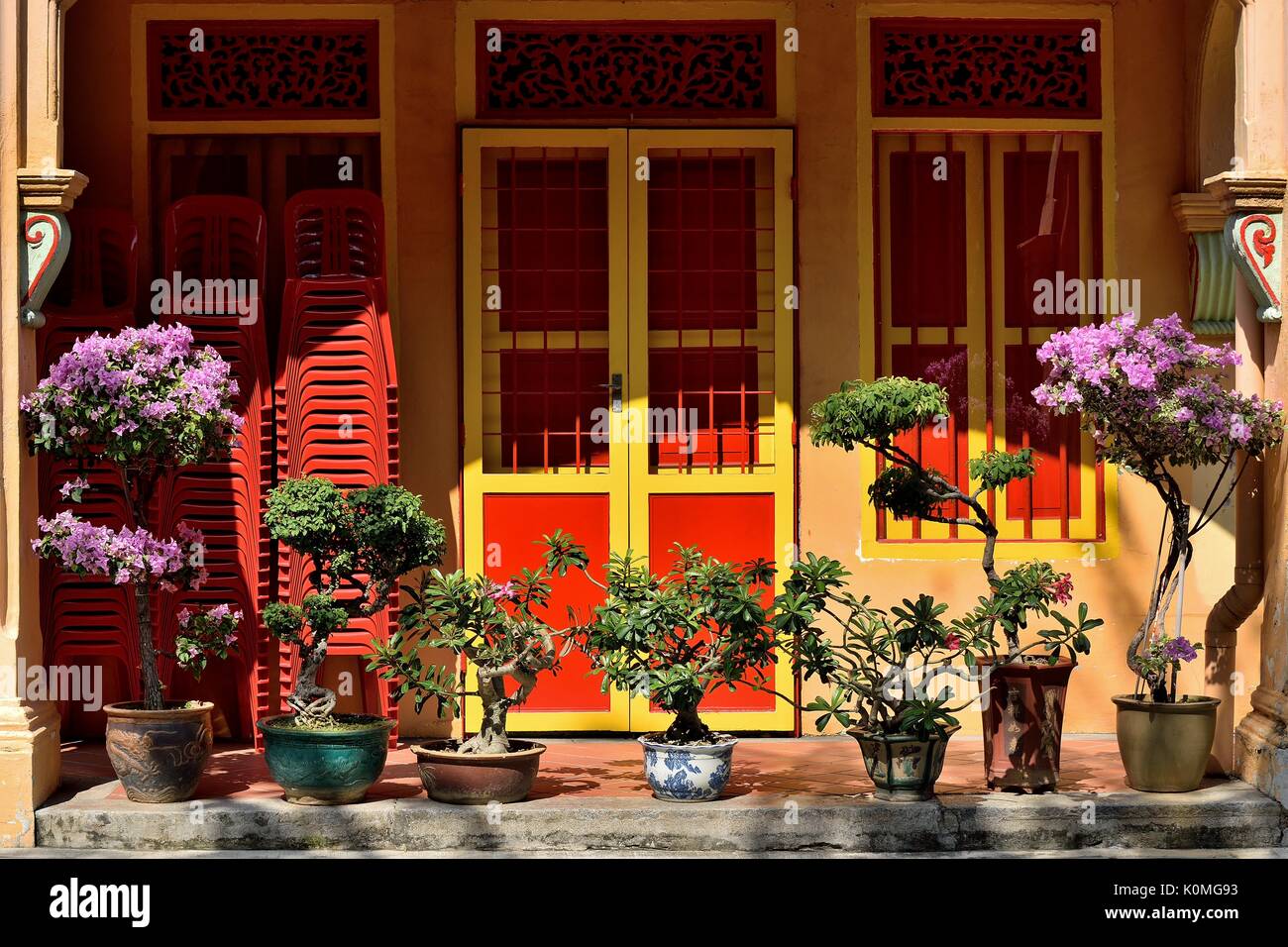 Negozio tradizionale casa piano terra esterno con il rosso e il giallo di porte e finestre e piante ornamentali sulla storica Joo Chiat Road, Singapore Foto Stock