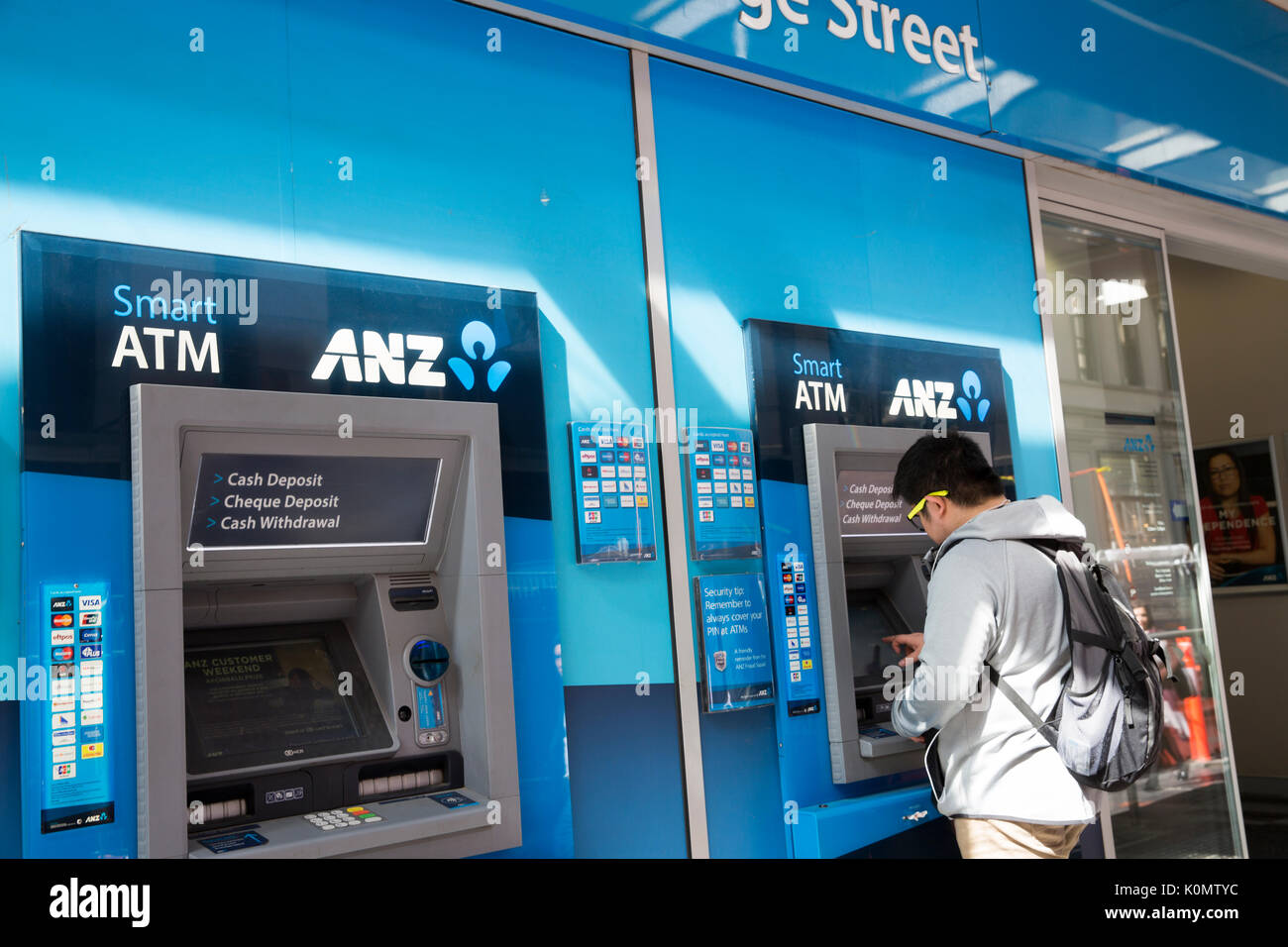 Uomo asiatico usando alla banca ANZ bancomat ATM nel centro di Sydney, Australia Foto Stock