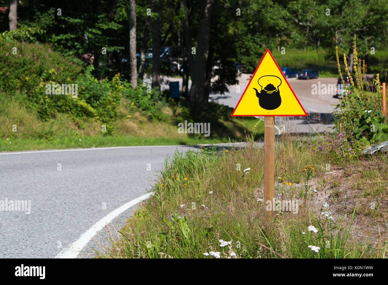 Cartello giallo con bollitore o teiera sul lato della strada. Insolito cartello stradale. Foto Stock