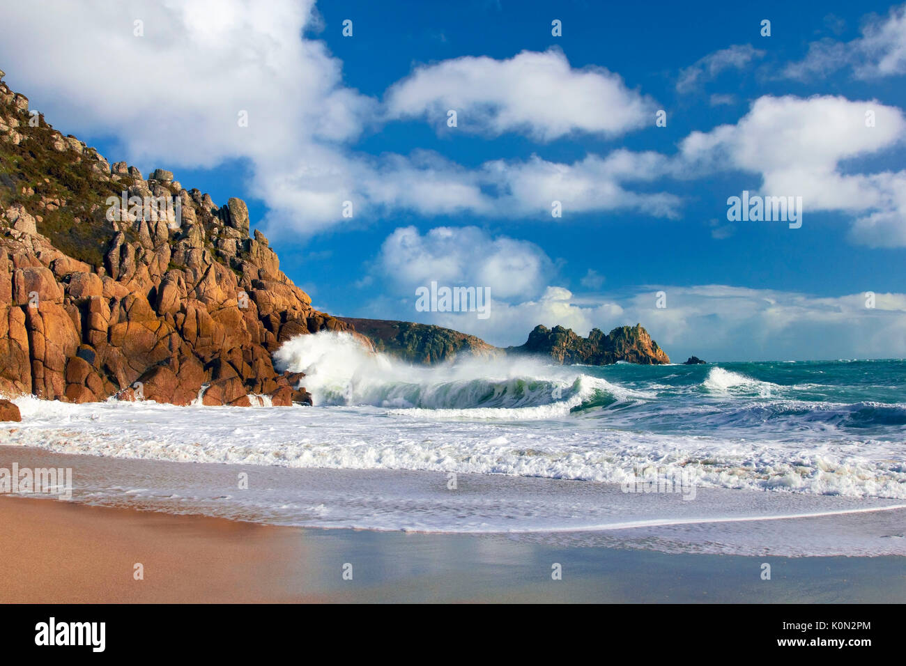 Una vista della spiaggia di porthcurno come onde infrangersi contro le scogliere Foto Stock