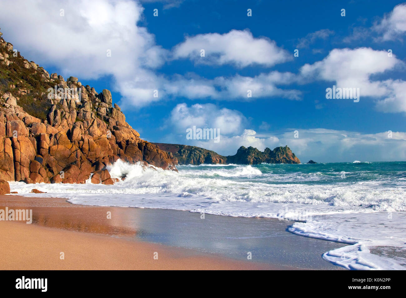 Una vista della spiaggia di porthcurno come onde infrangersi contro le scogliere Foto Stock