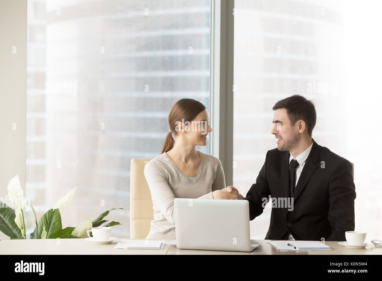 Imprenditore sorridente stringono le mani con imprenditrice in ufficio, Foto Stock