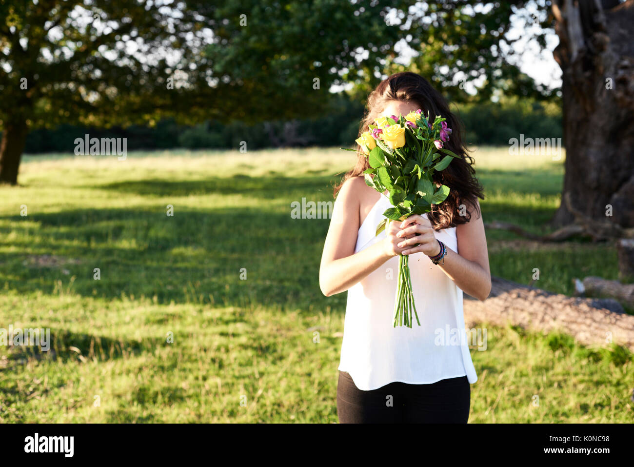 Hampstead Heath, Londra, Regno Unito, ritratto di una bella ragazza hidding il suo volto con un mazzo di fiori, Sunset Park Foto Stock