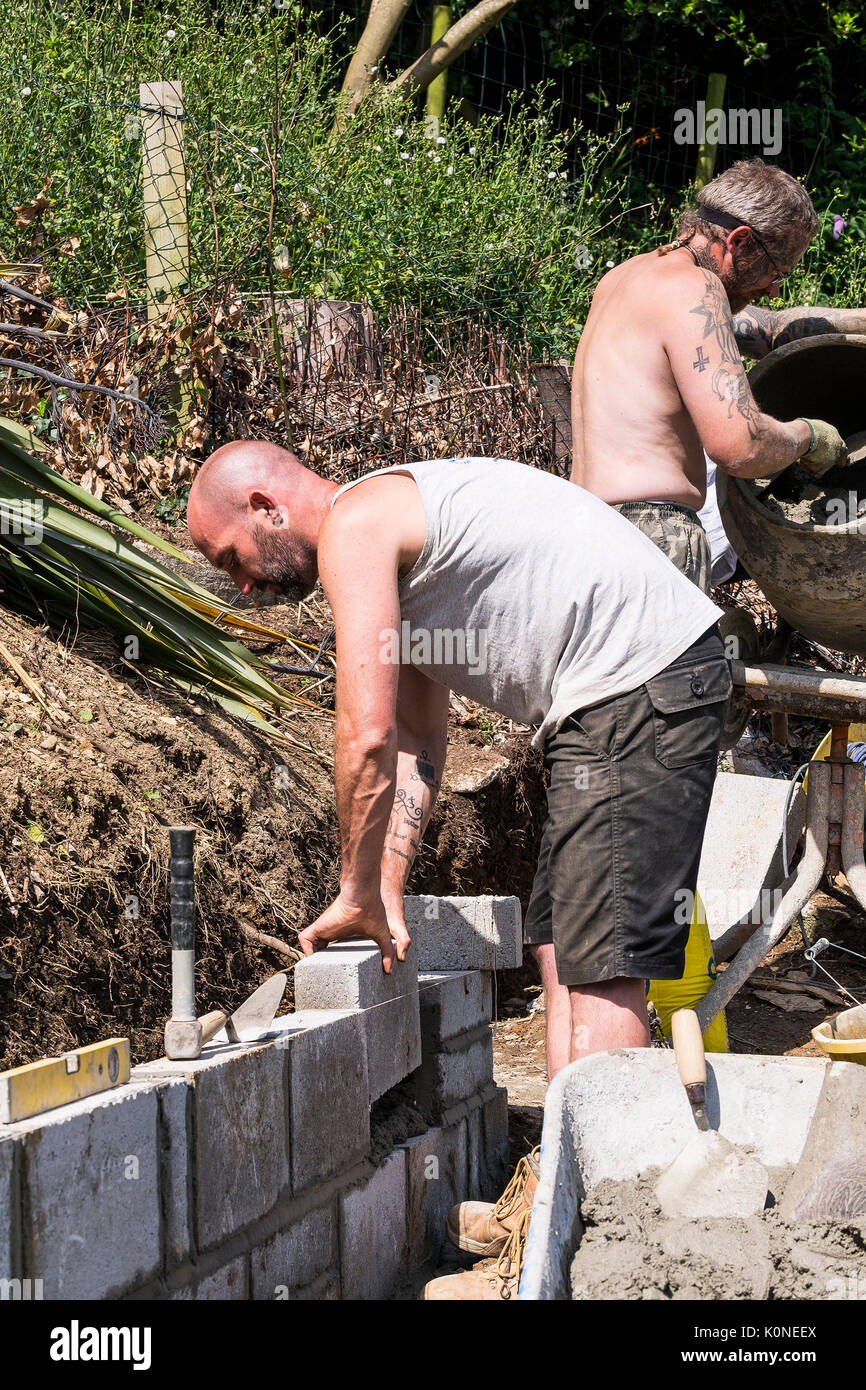 Lavoratori la costruzione di una parete del blocco su un sito di costruzione. Foto Stock