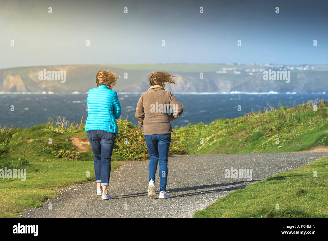 Due donne a piedi lungo il sentiero costiero durante il tempo ventoso. Foto Stock