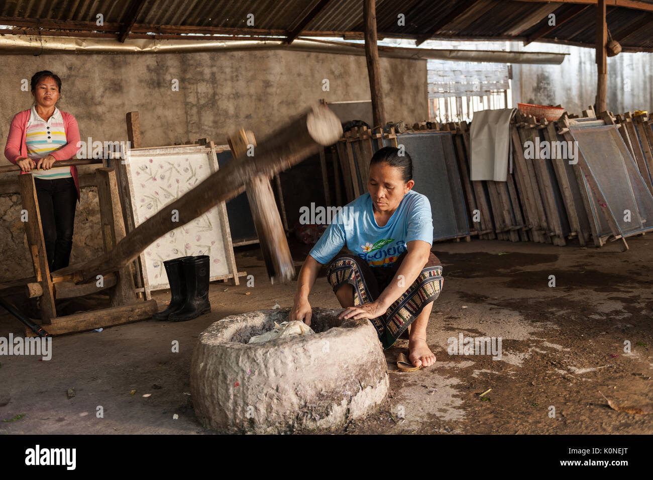 Una donna che gestisce un grande martello di legno che di libbre di Mulberry da polpa di corteccia nel processo di fabbricazione della carta in Xang Khong village, Luang Prabang, Laos.. Foto Stock