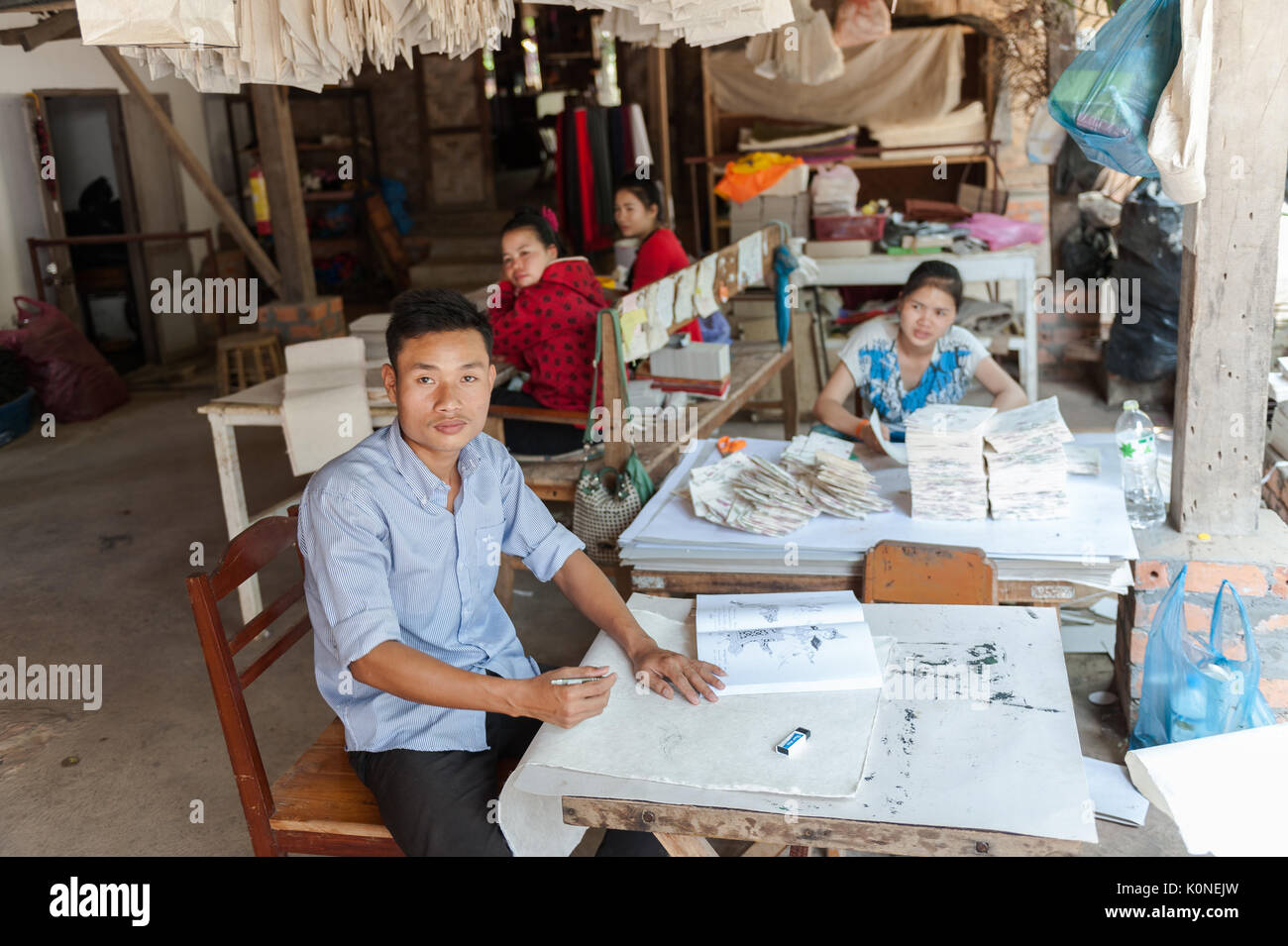Illustratore locale opera in un tradizionale studio di papermaking in un villaggio di Xhang Khong vicino a Luang Prabang, Laos. Foto Stock