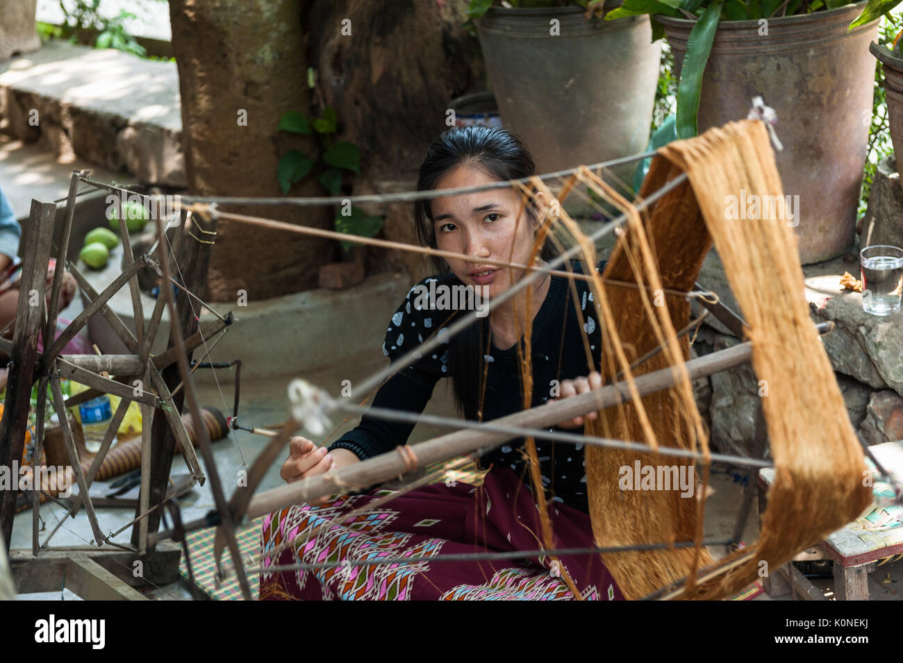 Una giovane donna Lao spin con filati di seta in Xhang Khong village. Conoscenza della produzione di tessuti di seta è passata dalle mamme e nonne per ragazze. Foto Stock