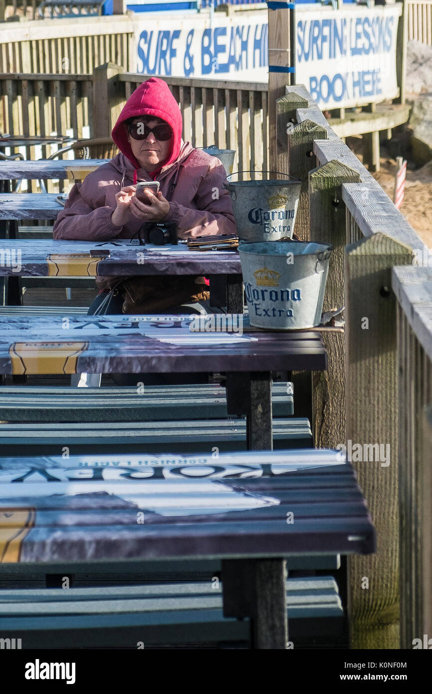 Una donna che indossa una felpa con cappuccio e occhiali da sole con il suo smartphone. Foto Stock