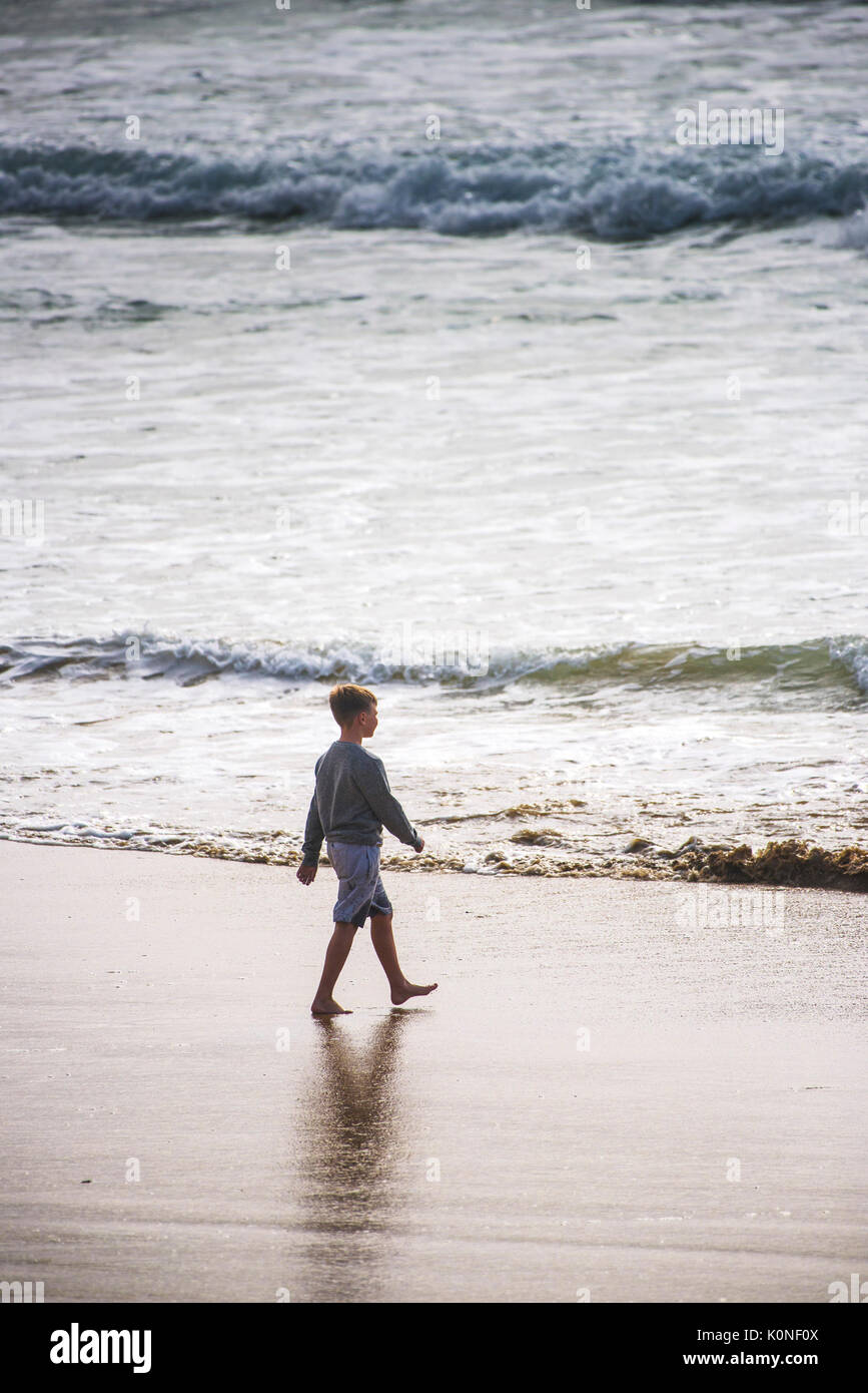 Un giovane ragazzo a camminare con fiducia verso il mare. Foto Stock