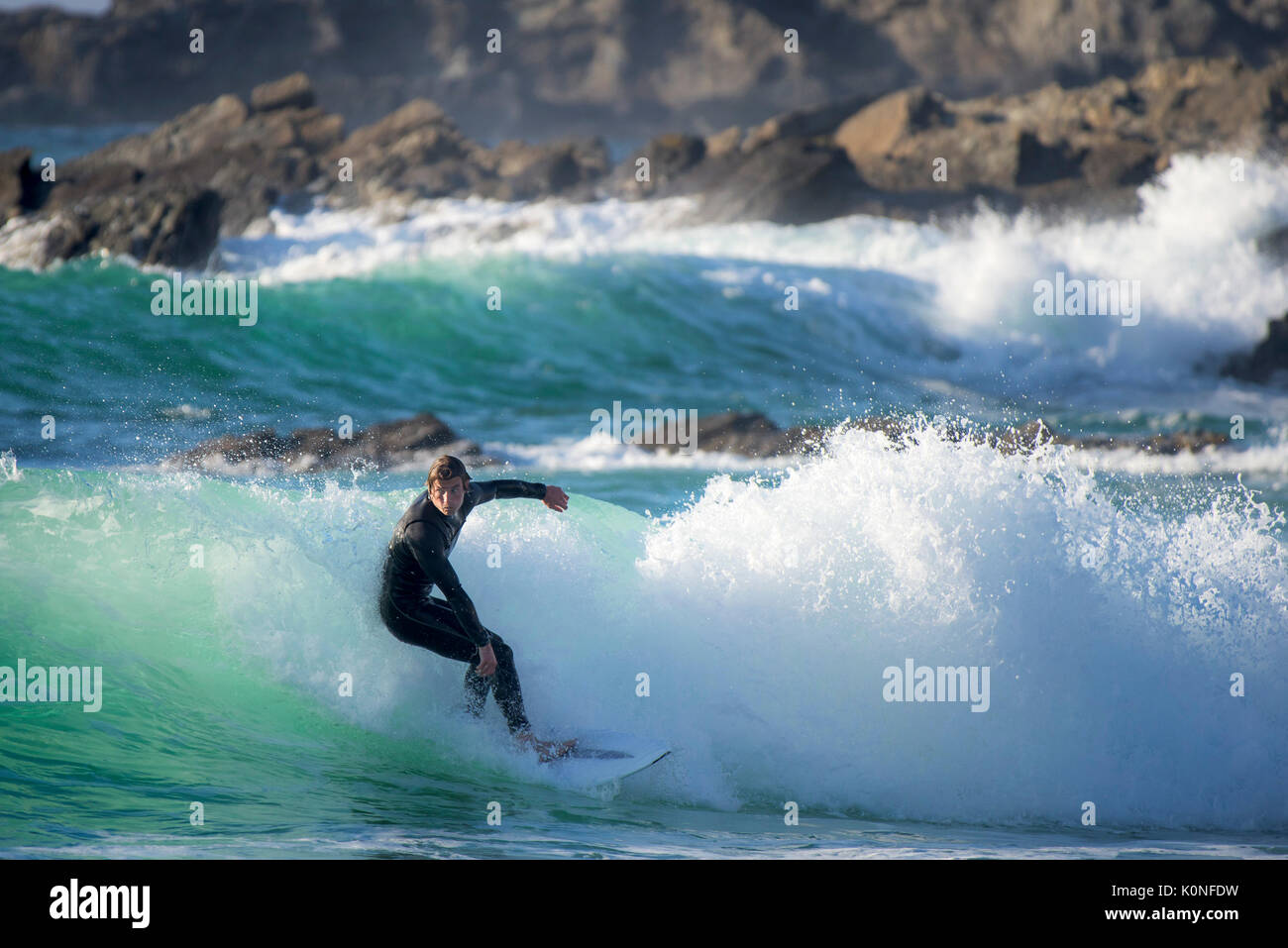 Un surfista a cavallo di un onda al Fistral Beach in Newquay. Foto Stock