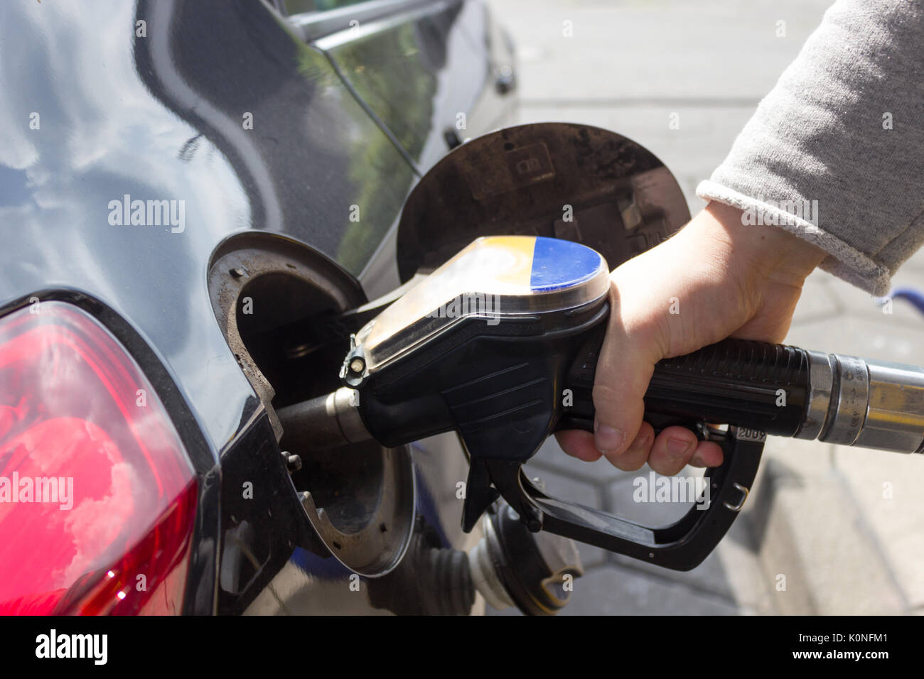 Close-up di mano il rifornimento auto del serbatoio di contenimento della pompa benzina ugello. Foto Stock