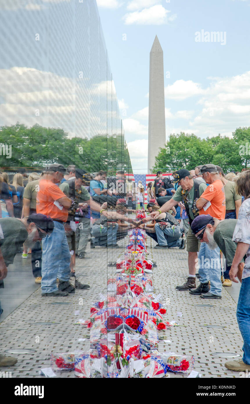 Visitatori guardare i nomi e gli artefatti a sinistra al Vietnam Veterans Memorial wall a Washington DC. Foto Stock