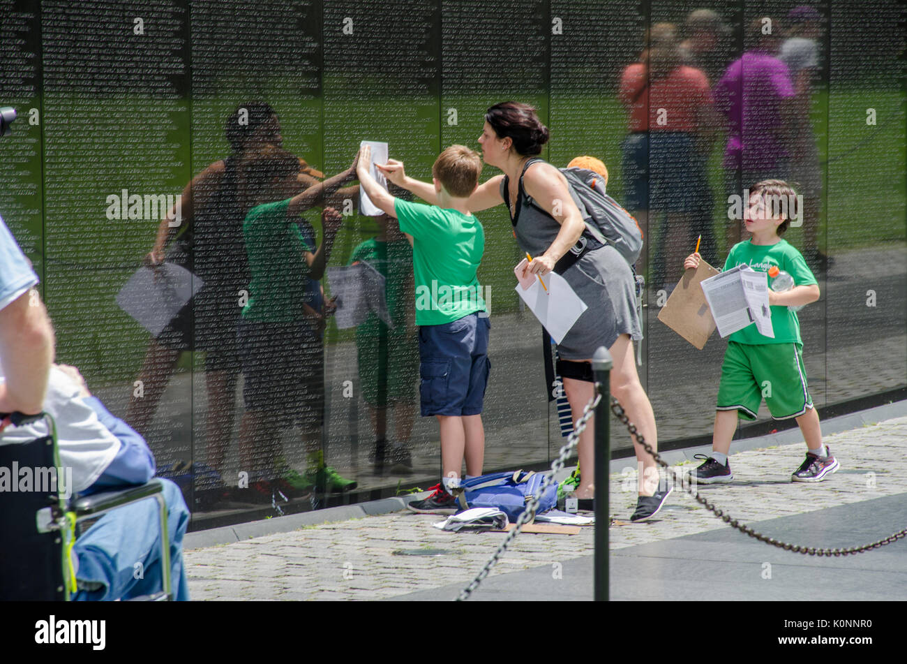 La scuola dei bambini, con l'aiuto del loro maestro, a matita di strisciamenti dei nomi sul Vietnam Veterans Memorial wall. Foto Stock