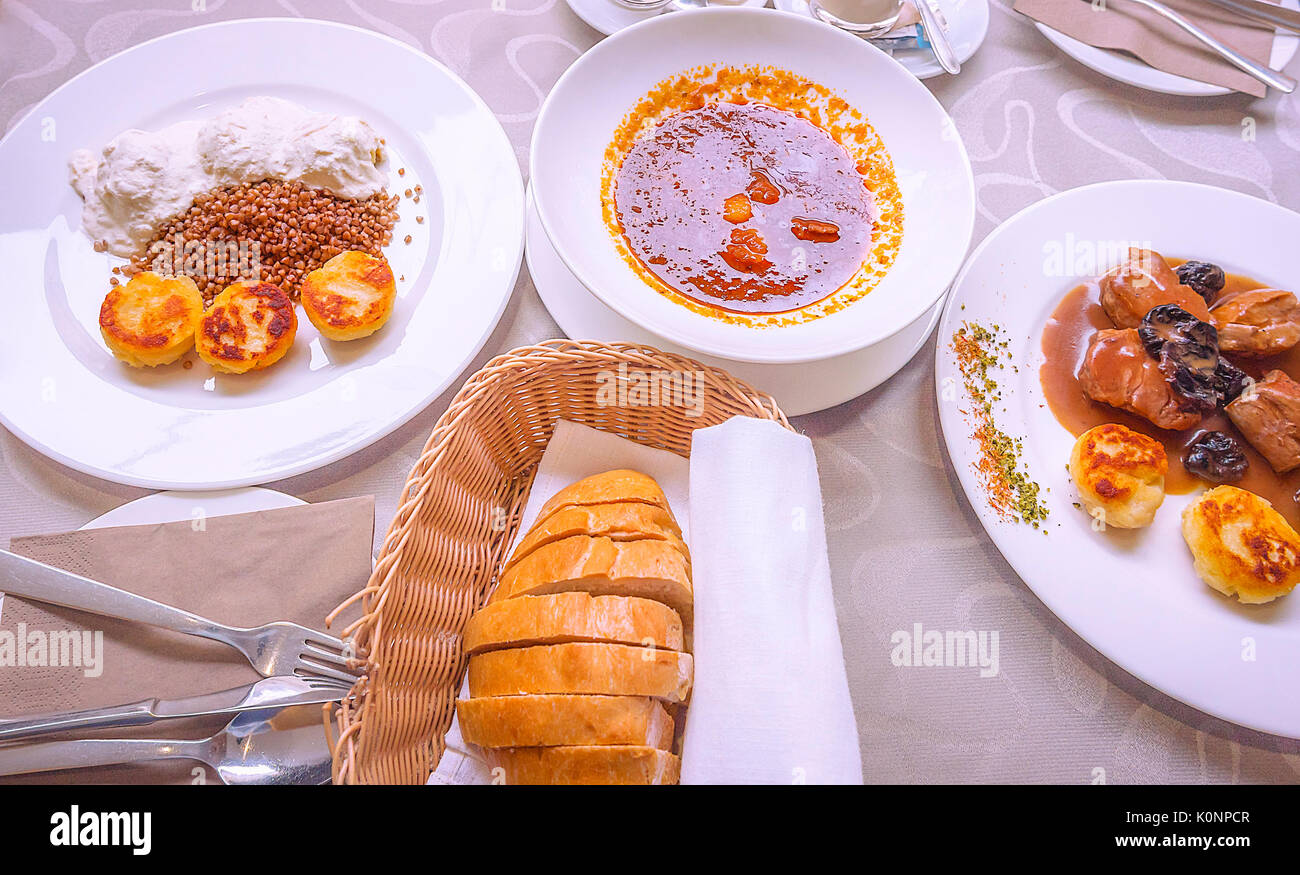 Tavolo con gustosi piatti sloveni, bollito gnocchetti di patate con cipolle e crema, e medaglioni di maiale con brandy alla prugna e salsa di prugne secche. Foto Stock