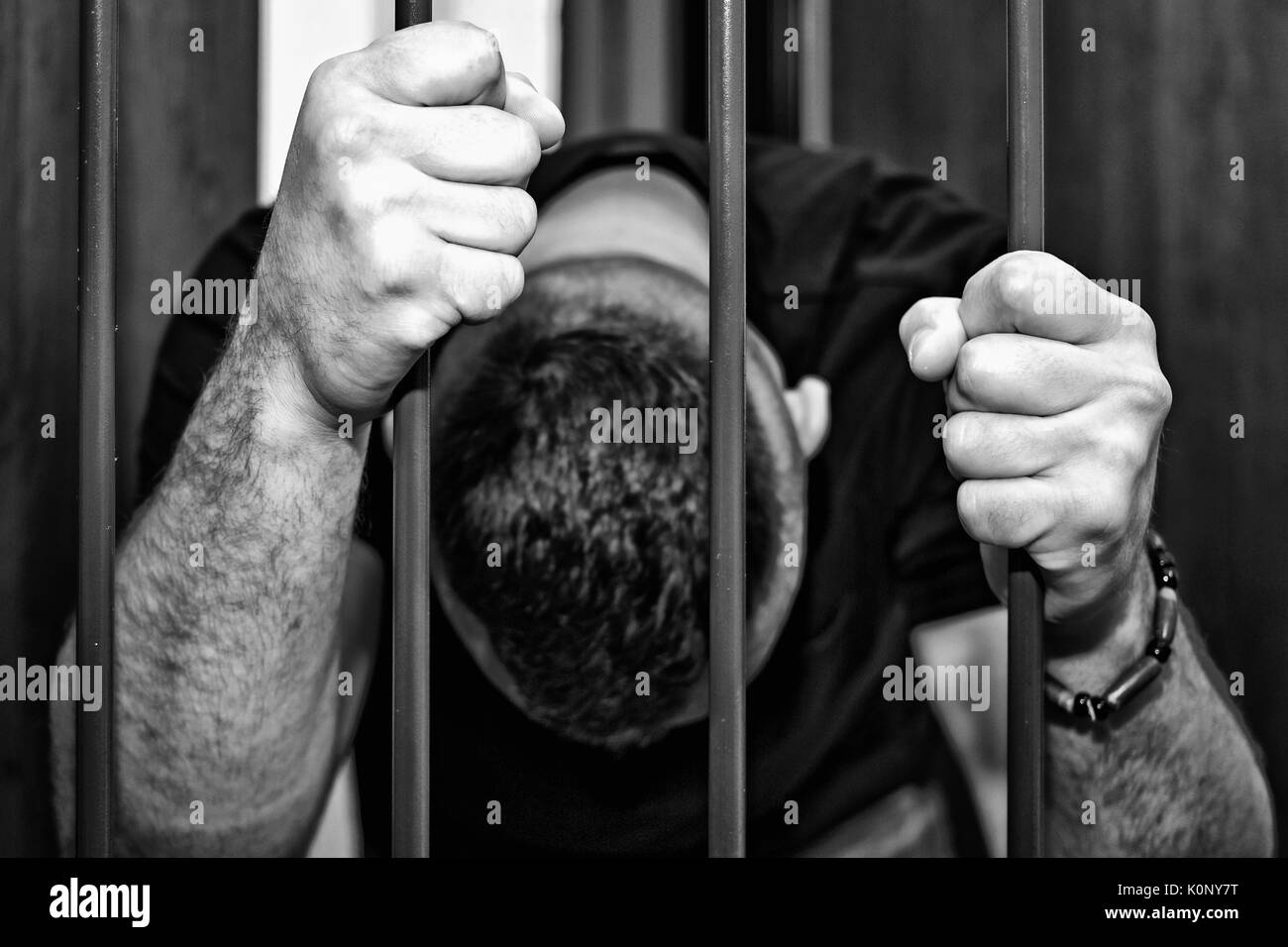 Abstract. Le mani del prigioniero su un traliccio di acciaio vicino. Il carcere, uomo in manette. Assassin, un assassino dietro le sbarre. Foto Stock