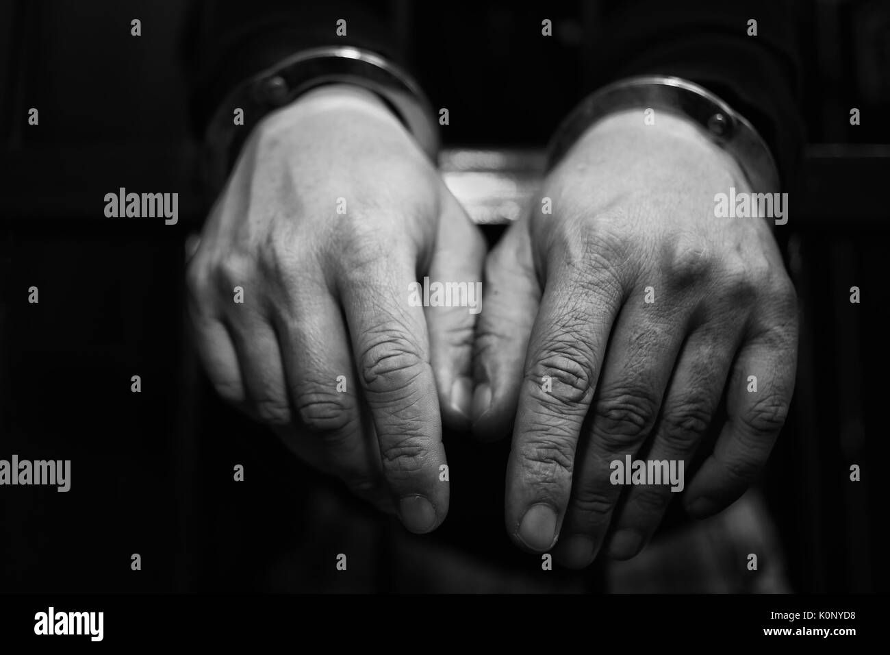 Abstract. Le mani del prigioniero su un traliccio di acciaio vicino. Il carcere, uomo in manette. Dettaglio delle mani con manette in acciaio. Foto Stock