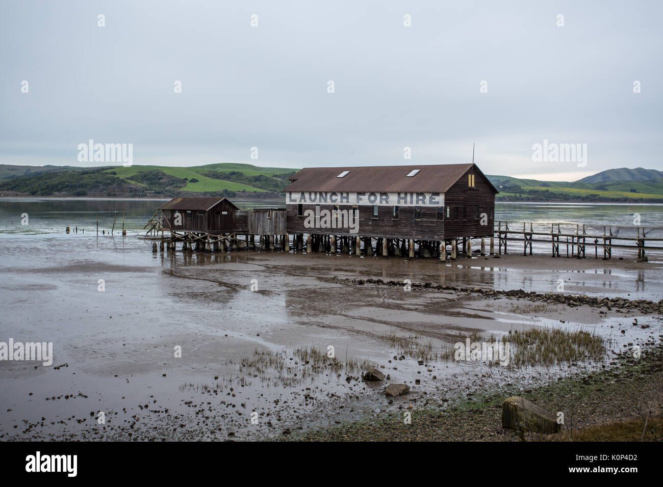 Lungo molo di lancio per barche in legno si trova sopra il fango durante la bassa marea Foto Stock