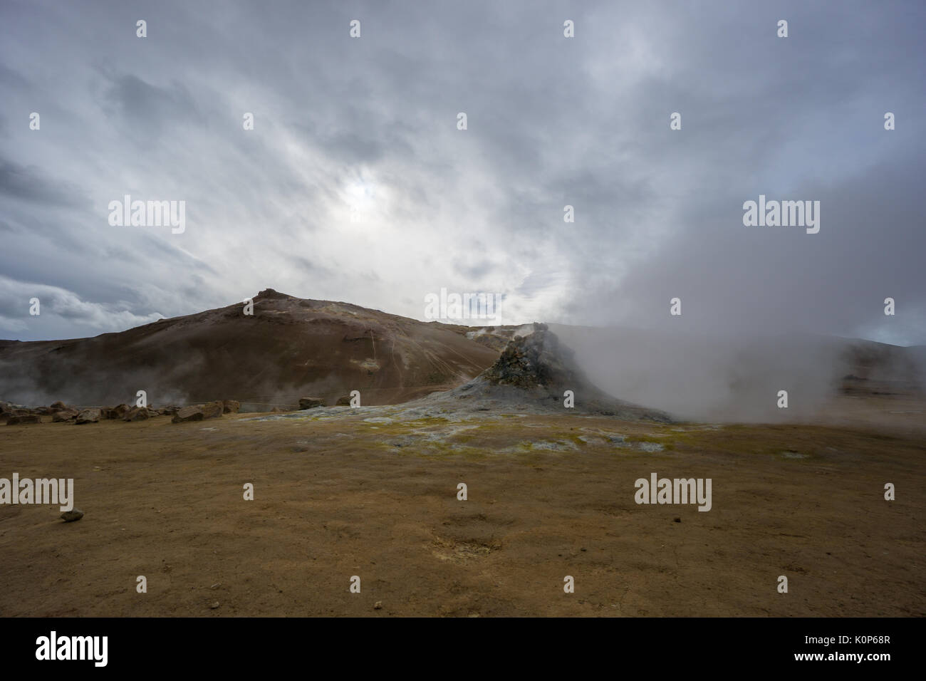 Islanda - Attivo di fumarole gas di spinta e il solfuro di idrogeno al di fuori del colorato in giallo terra di fronte a vulcano marrone Foto Stock