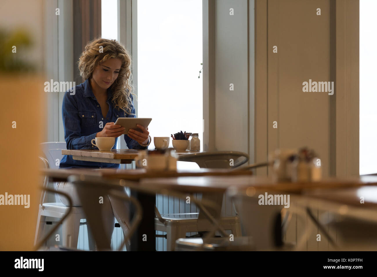 Giovane donna con tavoletta digitale mentre è seduto a tavola in cafe Foto Stock
