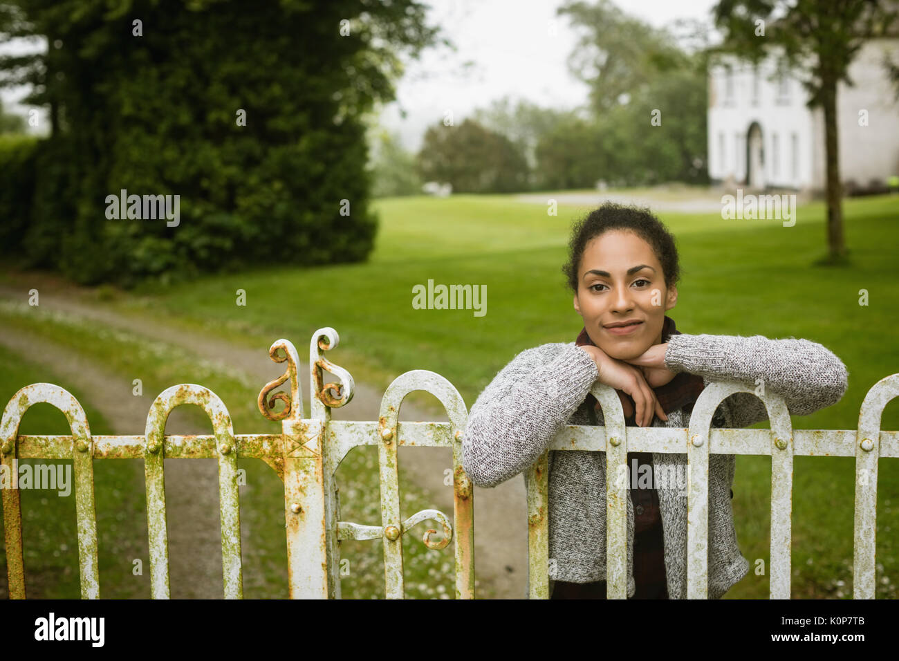 Bella donna appoggiata sul gate spiovente Foto Stock