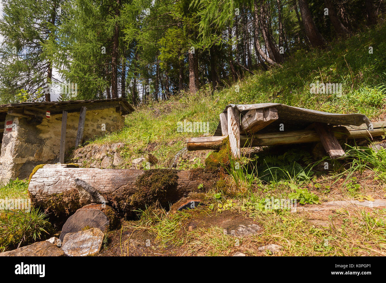 Vecchia fontana di legno in montagna e le foreste in background. foto in stile vintage. Foto Stock