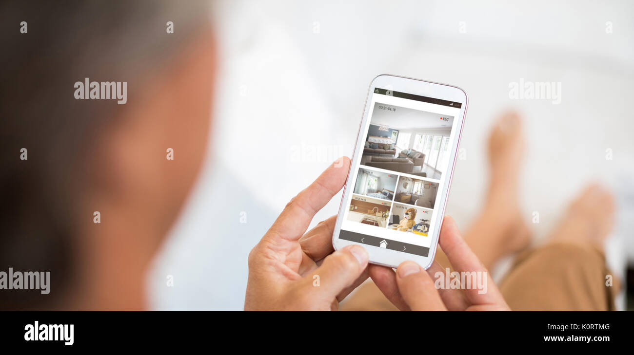 Interno della casa sul display mobile contro l'uomo tramite telefono cellulare nel soggiorno Foto Stock