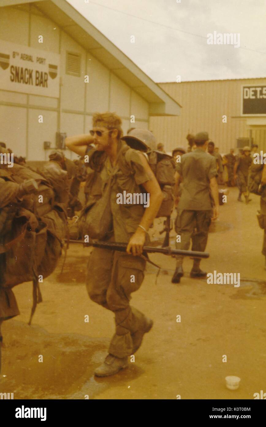 Un folto gruppo di soldati in uniforme con piena lotta ingranaggio, attende il trasporto al di fuori degli edifici a 8 porta antenna, Bien Hoa Air Base, Vietnam, 1964. Foto Stock