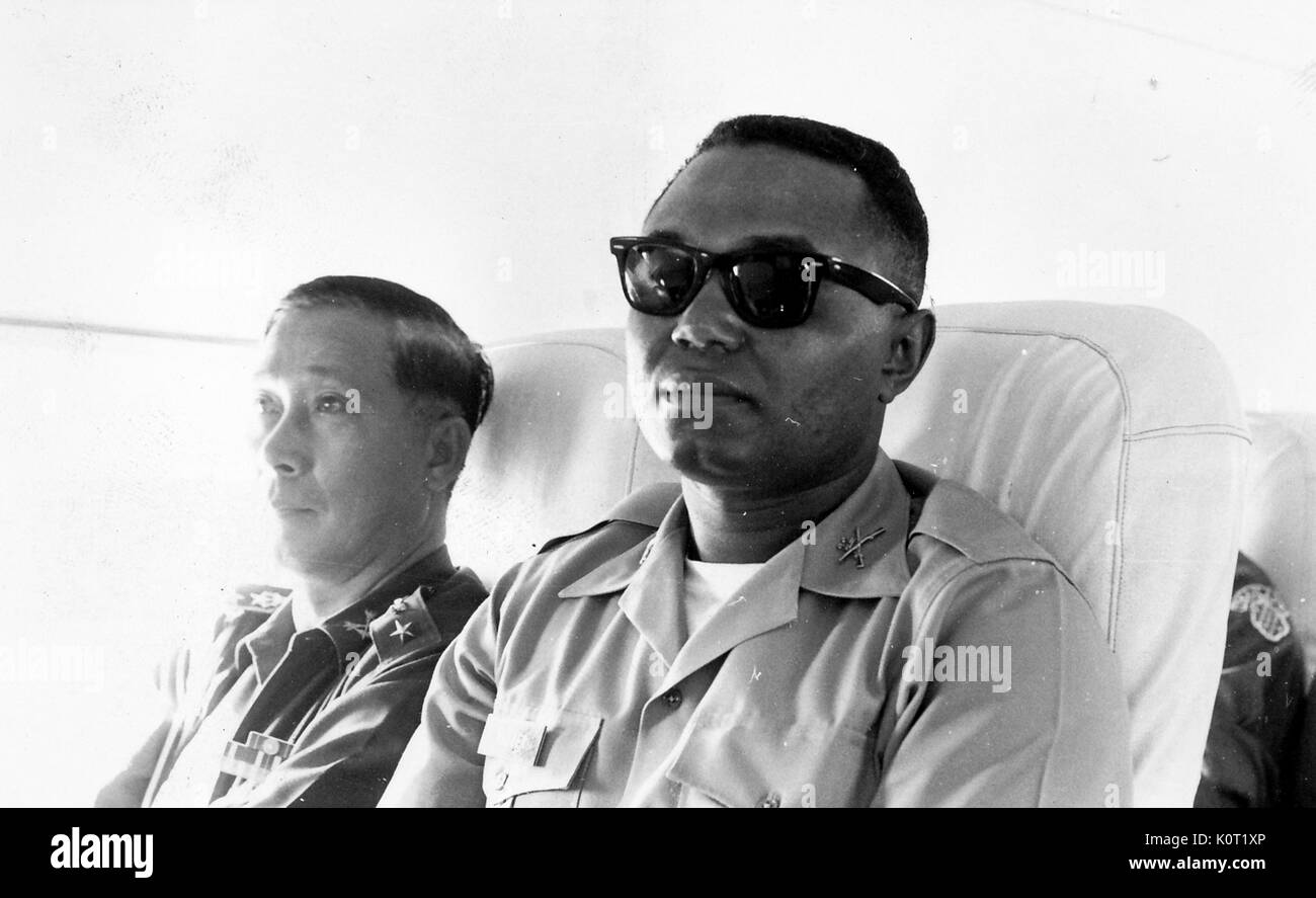 Afro-americano di esercito degli Stati Uniti il tenente al Walker seduto accanto a SP Col Sangad in un trasporto durante la Guerra del Vietnam, sfondo sovraesposte in foto originale, 1964. Foto Stock