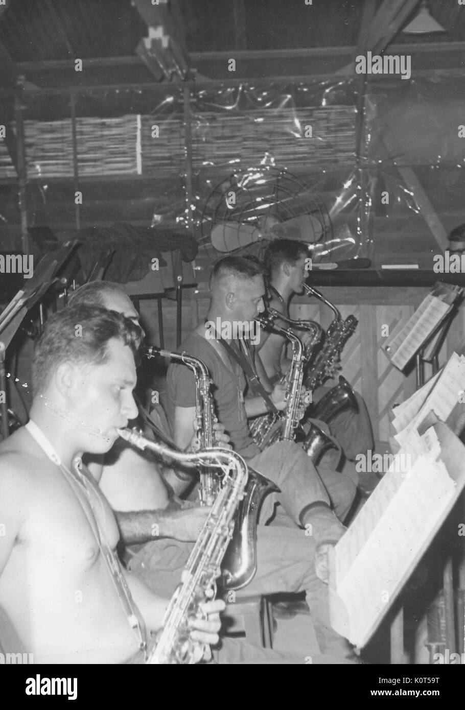 Una fotografia dei membri dell'esercito degli Stati Uniti Prima Divisione di Fanteria fascia giocare i loro strumenti mentre la lettura dal foglio di musica, molti dei membri non indossare le magliette, Vietnam, 1967. Foto Stock