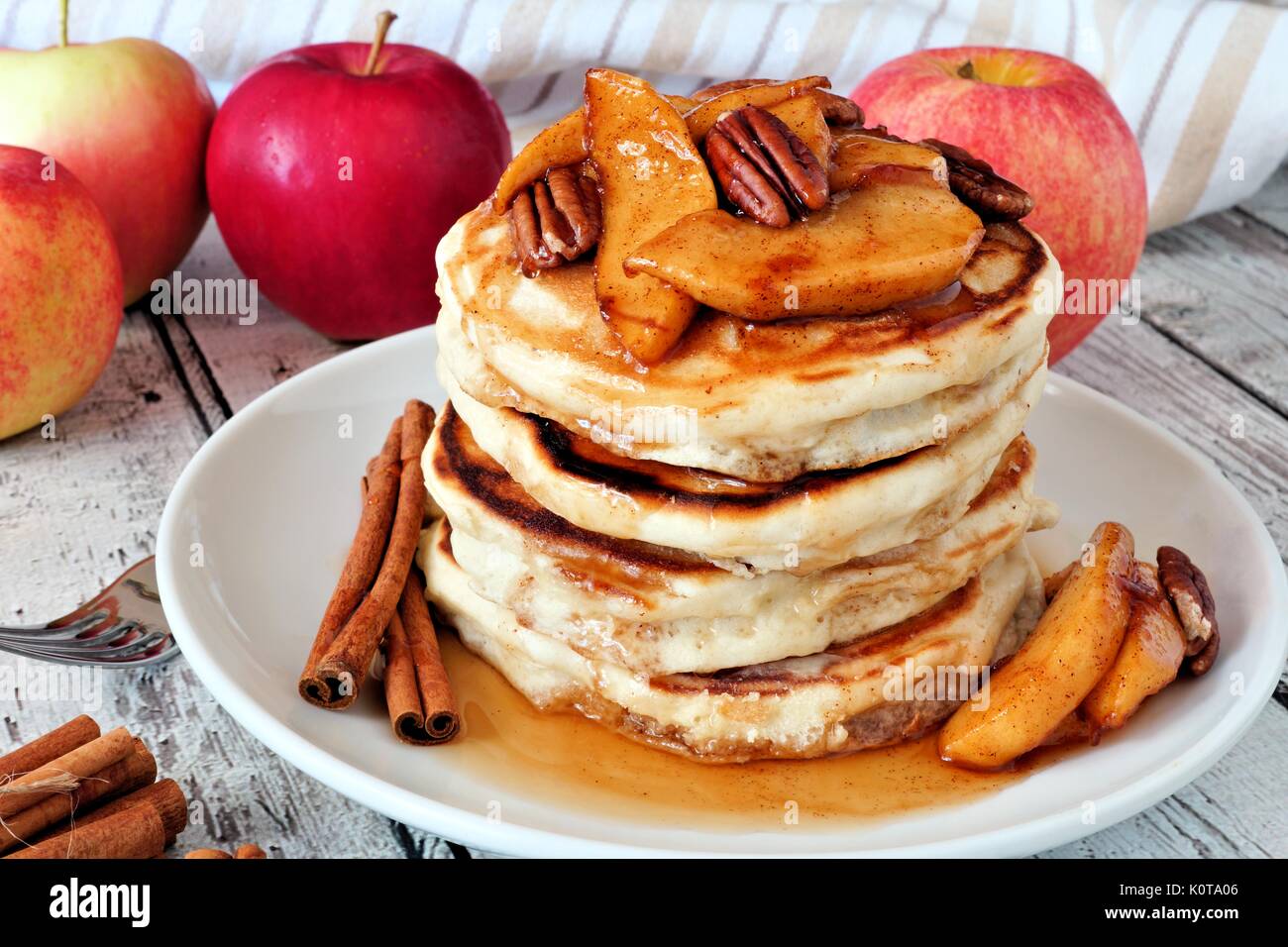 Autunno pancake stack con mele cotte, le noci pecan e cannella e rabboccato con sciroppo d'acero, tabella scena Foto Stock