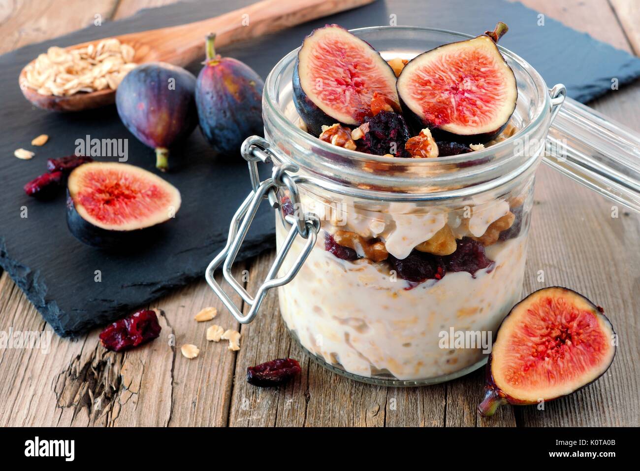 Vaso di notte autunno avena con red fichi, mirtilli e noci contro un rustico sfondo legno Foto Stock